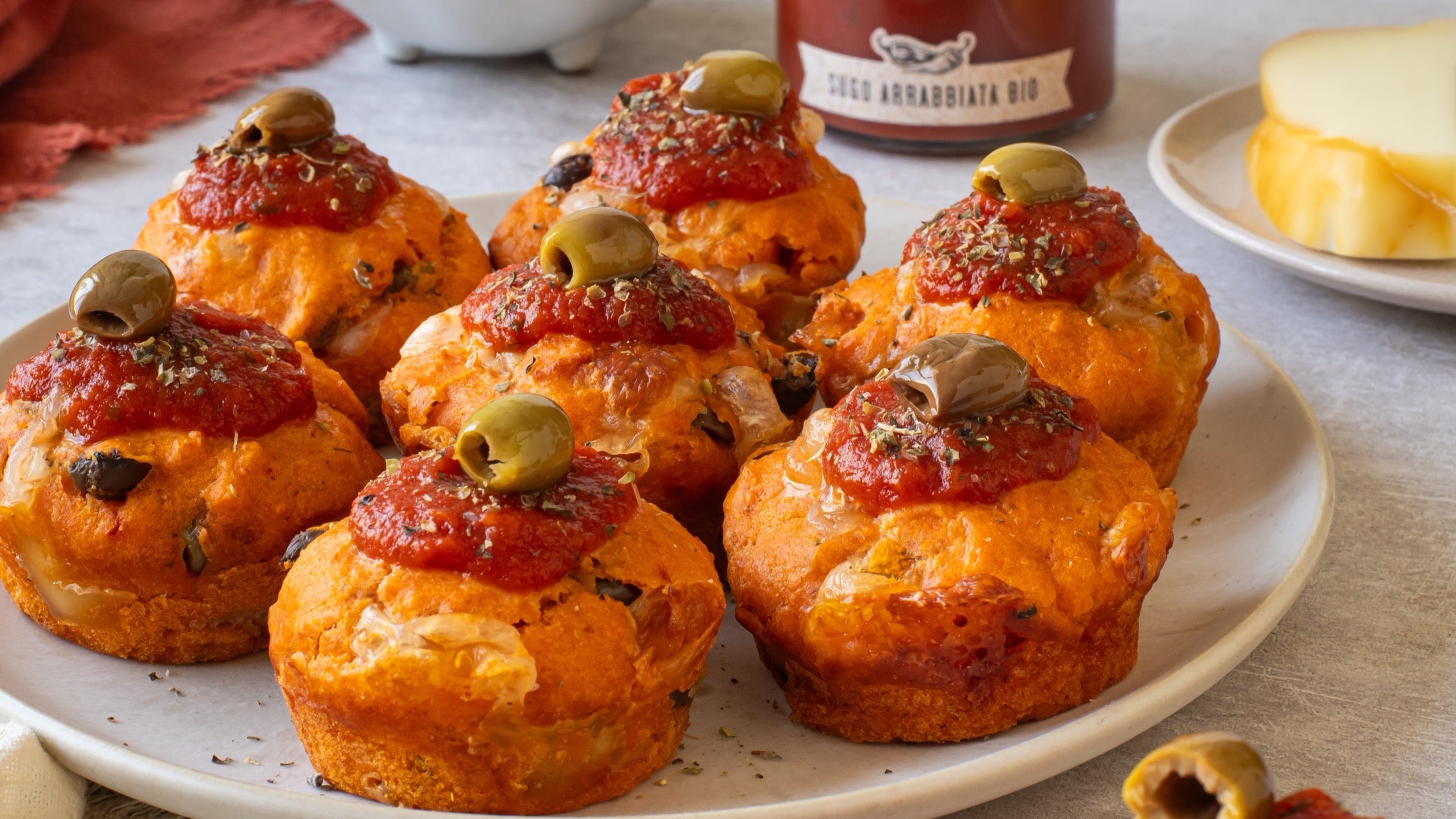 Muffins salati all'arrabbiata con provola e olive su un piatto bianco