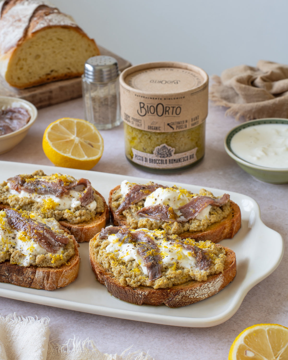 Bruschette con crema di broccolo romanesco Bio Orto servite accanto al pane casereccio, al limone e al vasetto