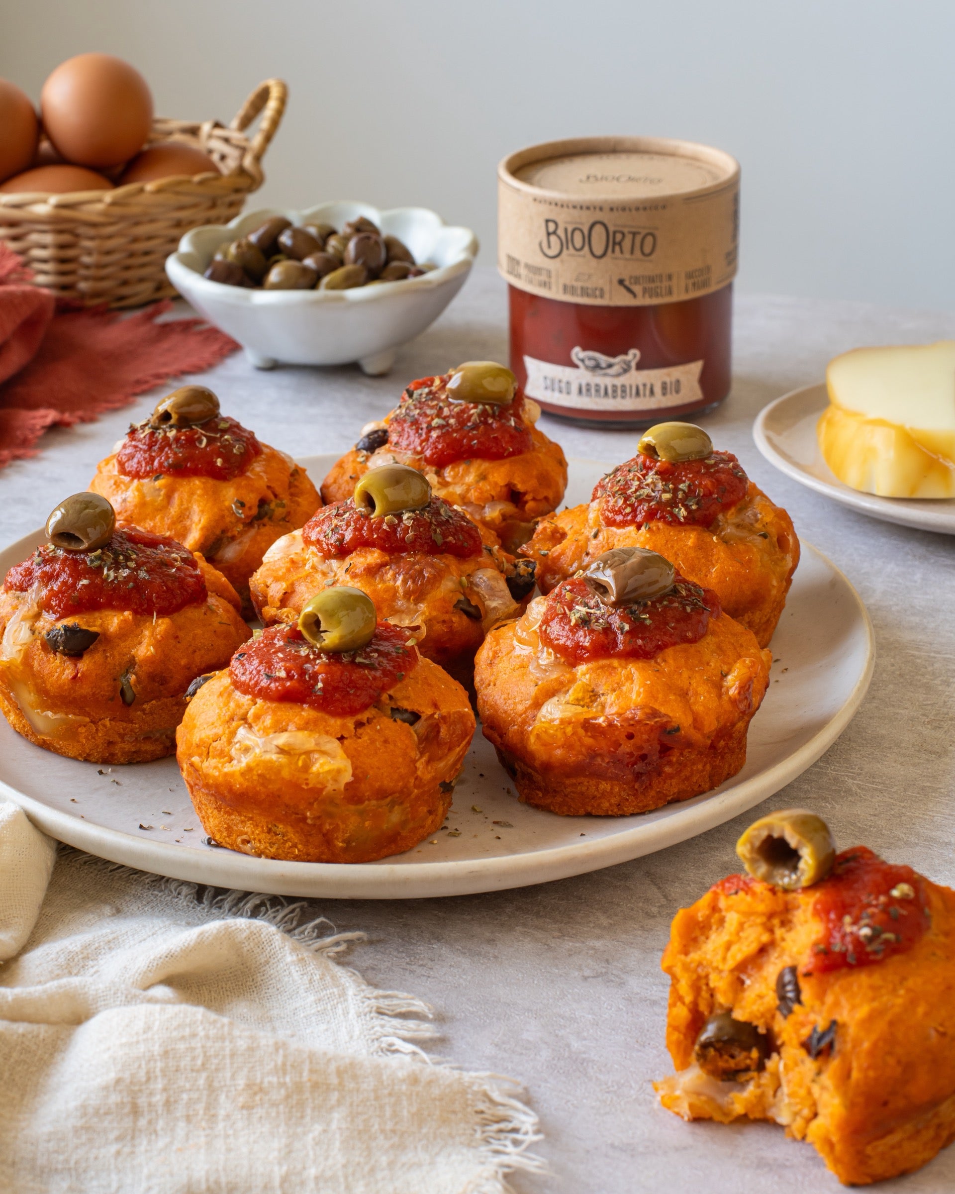 Muffins salati all'arrabbiata con provola e olive, serviti su un piatto accanto al Sugo Arrabbiata Bio Bio Orto
